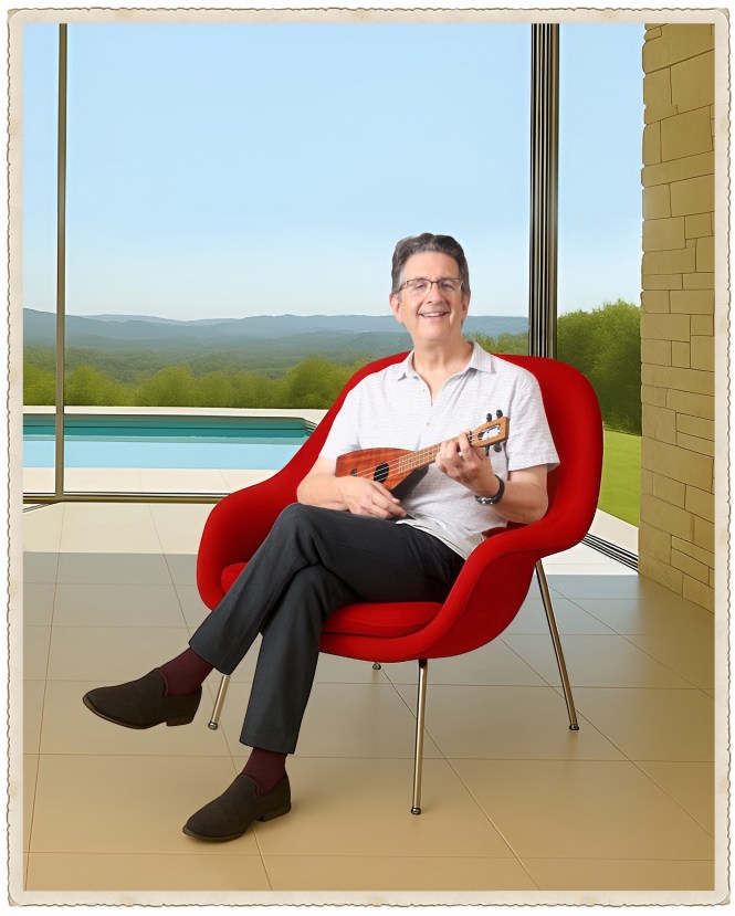 Jim Beloff with an ukulele sitting in a red chair.